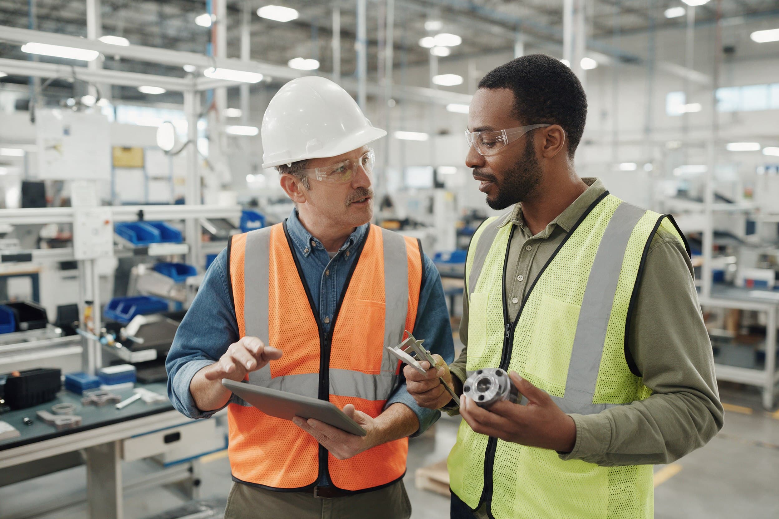 A production supervisor and a quality inspector reviewing a machined component together in a clean modern facility