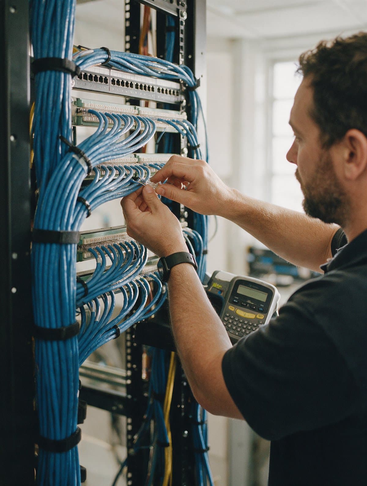 A cabling technician terminating cables on a patch panel